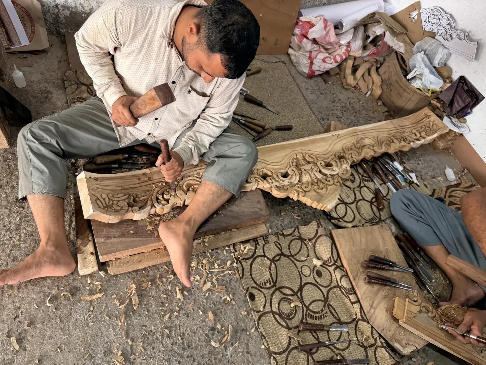 Master artisan carving solid teak at Ravensaa workshop